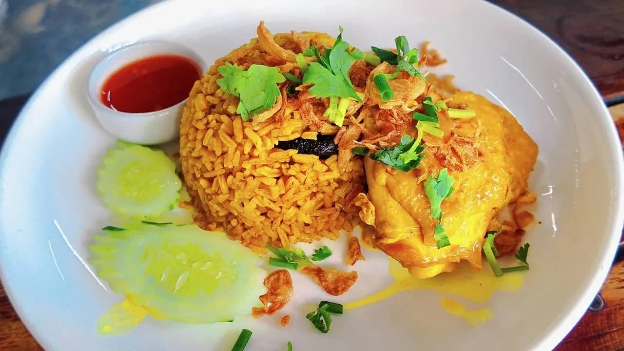 ข้าวหมกไก่สีเหลือง โรยหอมเจียว มีแตงกวาและน้ำจิ้ม